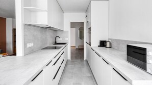 Una cocina moderna con armarios blancos, un grifo negro y un horno empotrado.