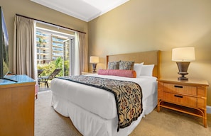 A hotel room with a large bed, two bedside lamps, a wooden nightstand, and a view of a building through a glass door.