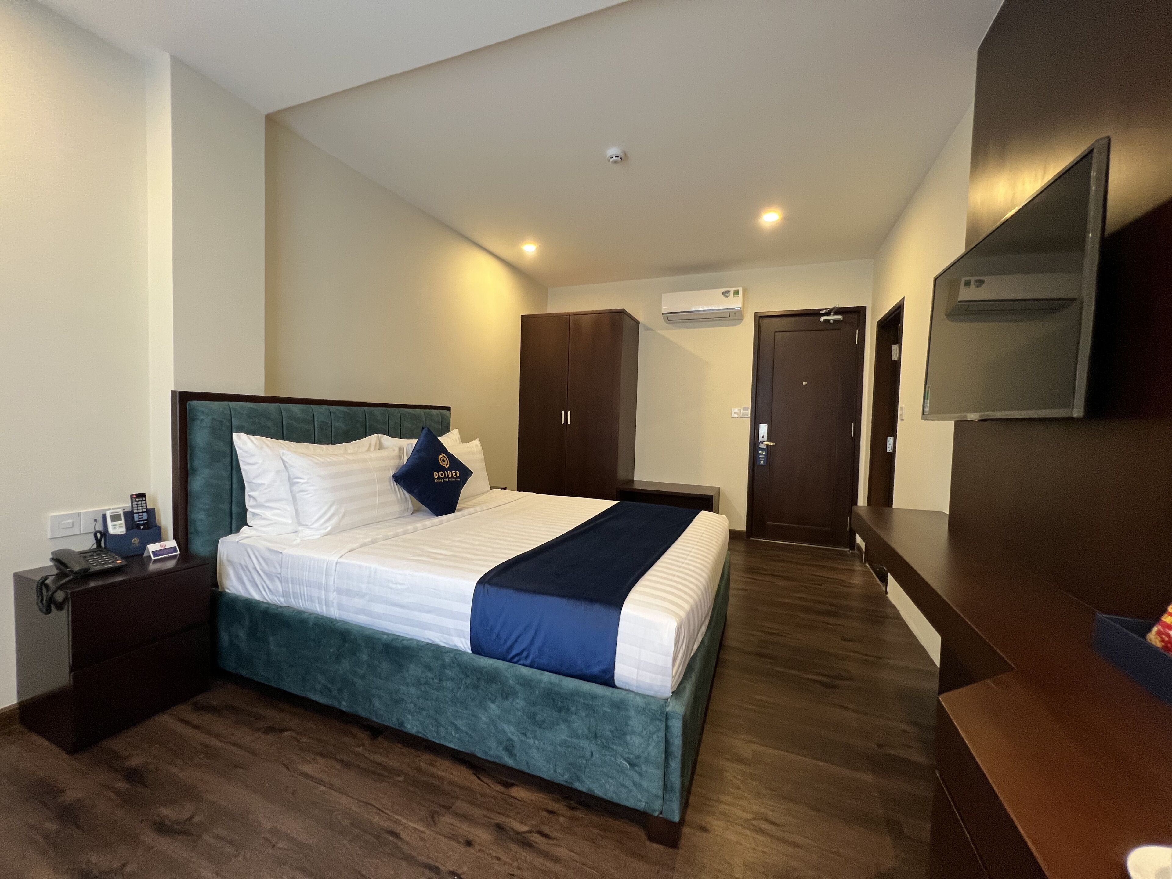A hotel room with a bed, a desk, a wardrobe, and a TV.