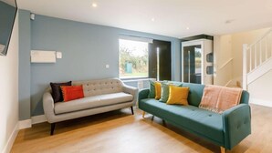 A living room with a grey sofa, a teal sofa, and a wooden floor. - Fully Accessible-Disabled Adapted-Hot Tub-Pets (Coughton)