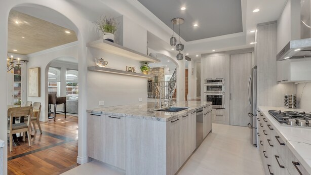 Una cocina moderna con una isla central, electrodomésticos de acero inoxidable y un comedor de madera.