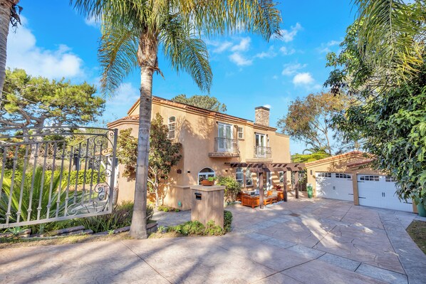 Una casa de dos pisos con un patio, un jardín cercado y un garaje.
