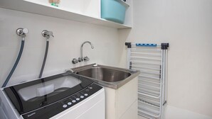 A modern bathroom with a built-in washing machine, a sink, and a towel rack. - Renovated 3 bed Unit with Views (Umina Beach)