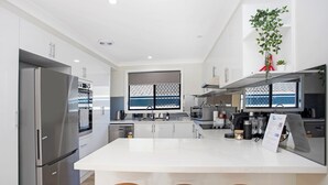 A modern kitchen with a central island, stainless steel appliances, and a large window. - Renovated 3 bed Unit with Views (Umina Beach)