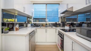 Een moderne keuken met witte kastjes, een inbouwoven en een groot raam voor natuurlijk licht.
