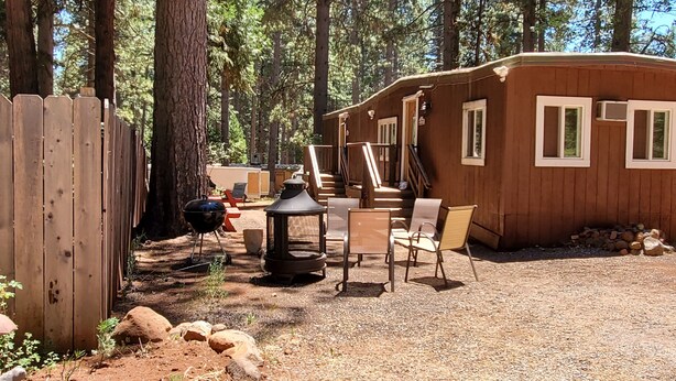 A small wooden cabin with a patio area, a grill, and a lantern.
