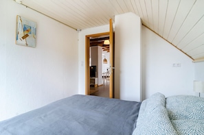 Ein Schlafzimmer mit einem Bett, einem Sofa, einem Gemälde und einem Durchgang zu einem Essbereich.
