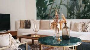 A living room with a round green table, a sofa, and a large plant in the background. - Villa M Canggu (Canggu)