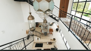 A spacious indoor area with a staircase, a hanging light fixture, and a view of the outdoors. - Villa M Canggu (Canggu)