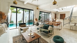A spacious living area with a pool, modern furniture, and a staircase leading to an upper level. - Villa M Canggu (Canggu)