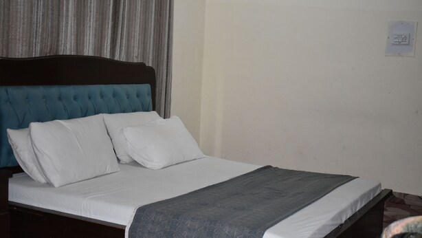 A bed with a dark headboard, white bedding, and a grey blanket. - Town Palace Guest House (Mekhtar)