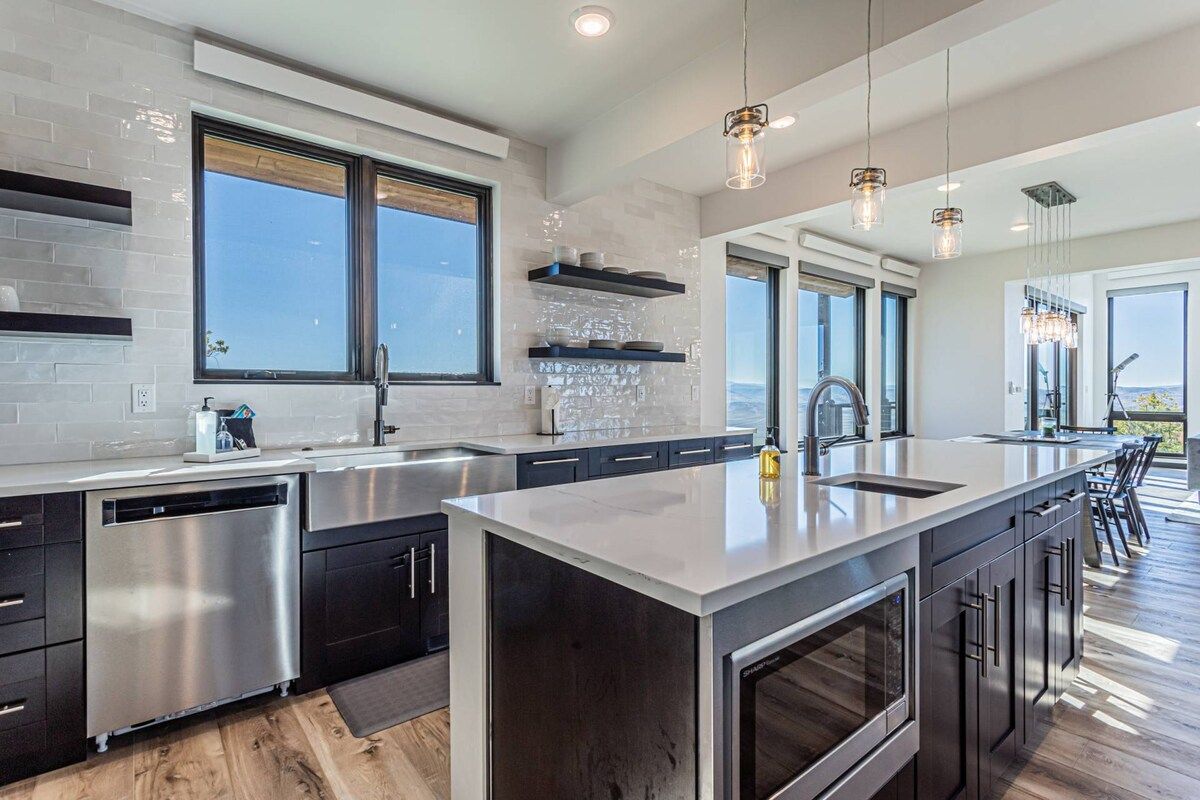 Una cocina moderna con una isla central, electrodomésticos de acero inoxidable y ventanas amplias.