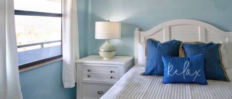 A bedroom with a bed, a nightstand, a lamp, and a window with curtains.