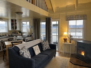 A cozy living room with a sofa, a fireplace, a dining area, and a kitchen.