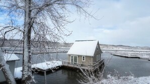 Una casa flotante atracada en el puerto deportivo con un paisaje nevado al fondo.