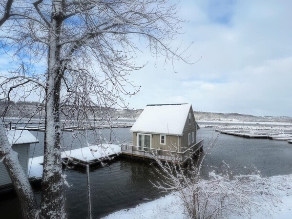 A houseboat docked at a marina with a snowy landscape in the background.