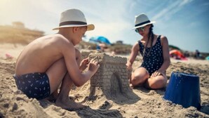 Two people building a sandcastle on a beach. - The "Lily Pad" Boatel Houseboat (Sabula)