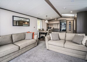 Un interior de autocaravana moderna con dos sofás, una mesa de comedor y una zona de cocina.
