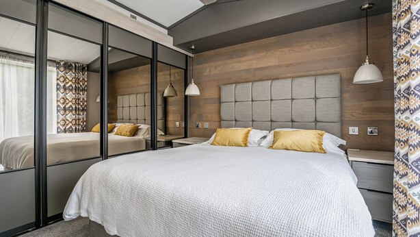 Una camera da letto moderna con un letto grande, comodini, uno specchio e un lampadario.