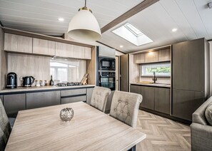 Una cocina moderna con zona de comedor, muebles de madera, cocina a gas y tragaluz.