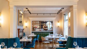 Un restaurant avec des banquettes et des tables, un bar et une vue sur la rue.