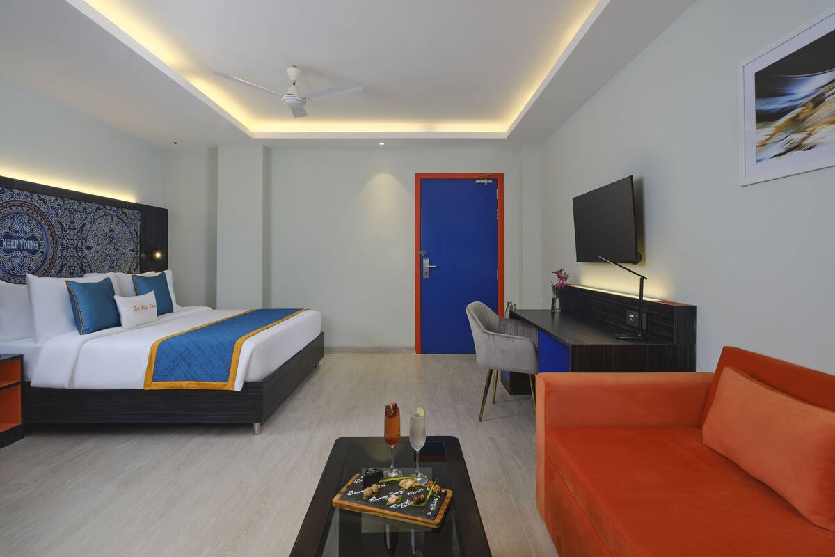 A hotel room with a bed, a desk, a TV, a coffee table, and a couch.