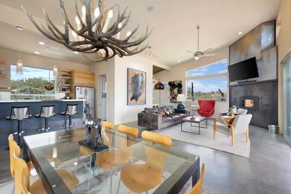Un espacio habitable moderno con una mesa de comedor de vidrio, sofás de cuero y una chimenea.