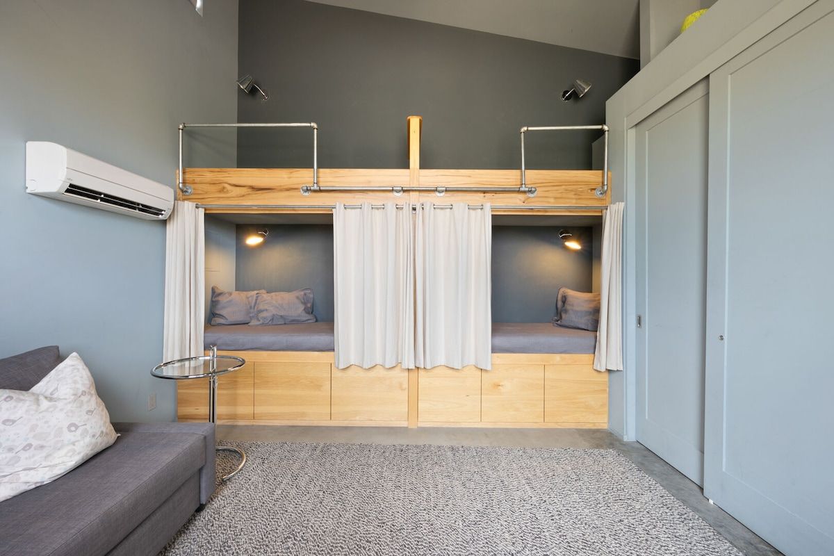 A compact room with a bunk bed, a small table, and a sofa.