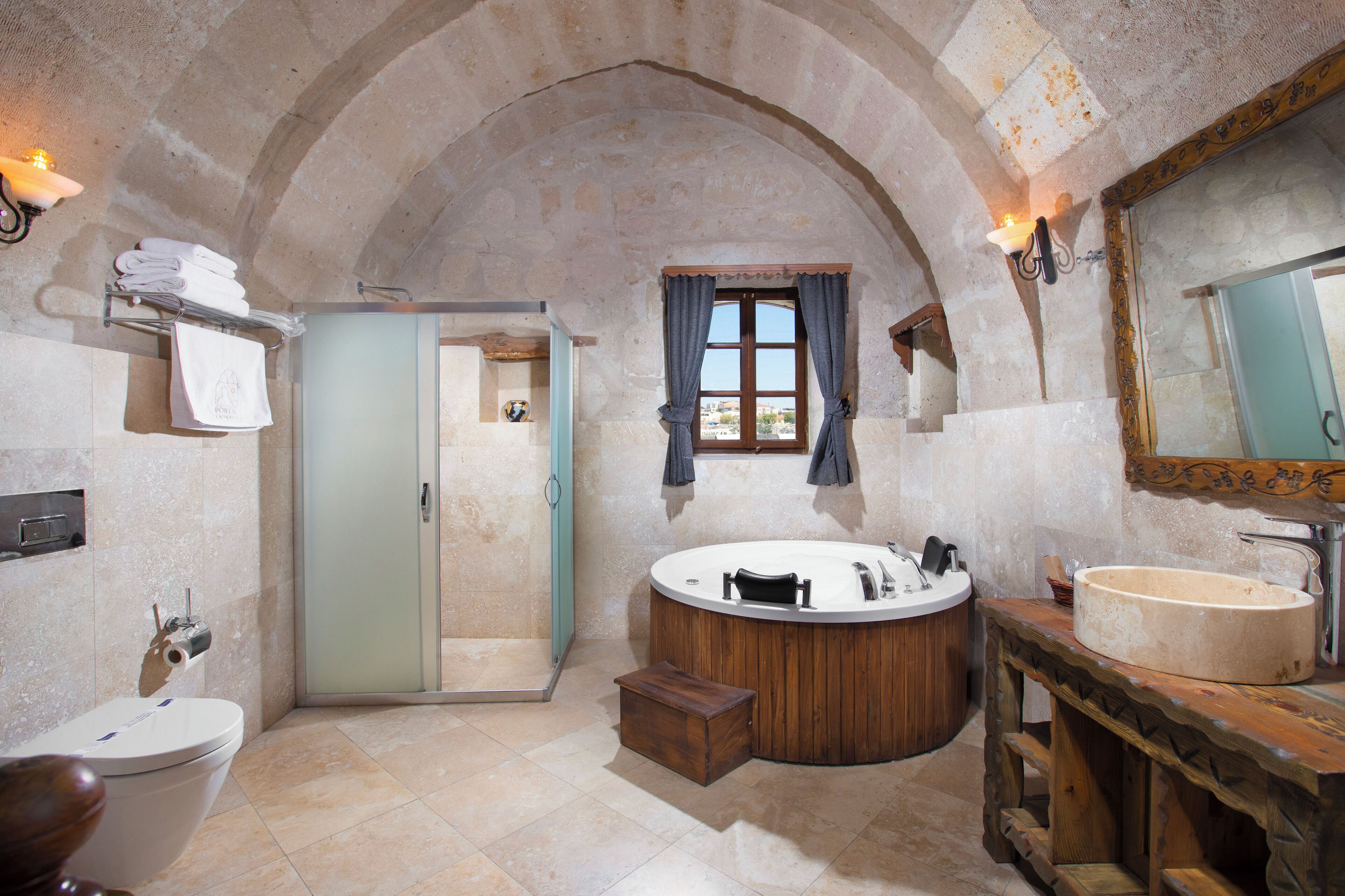 Une salle de bain avec une arche en pierre, une baignoire, un lavabo et une douche.