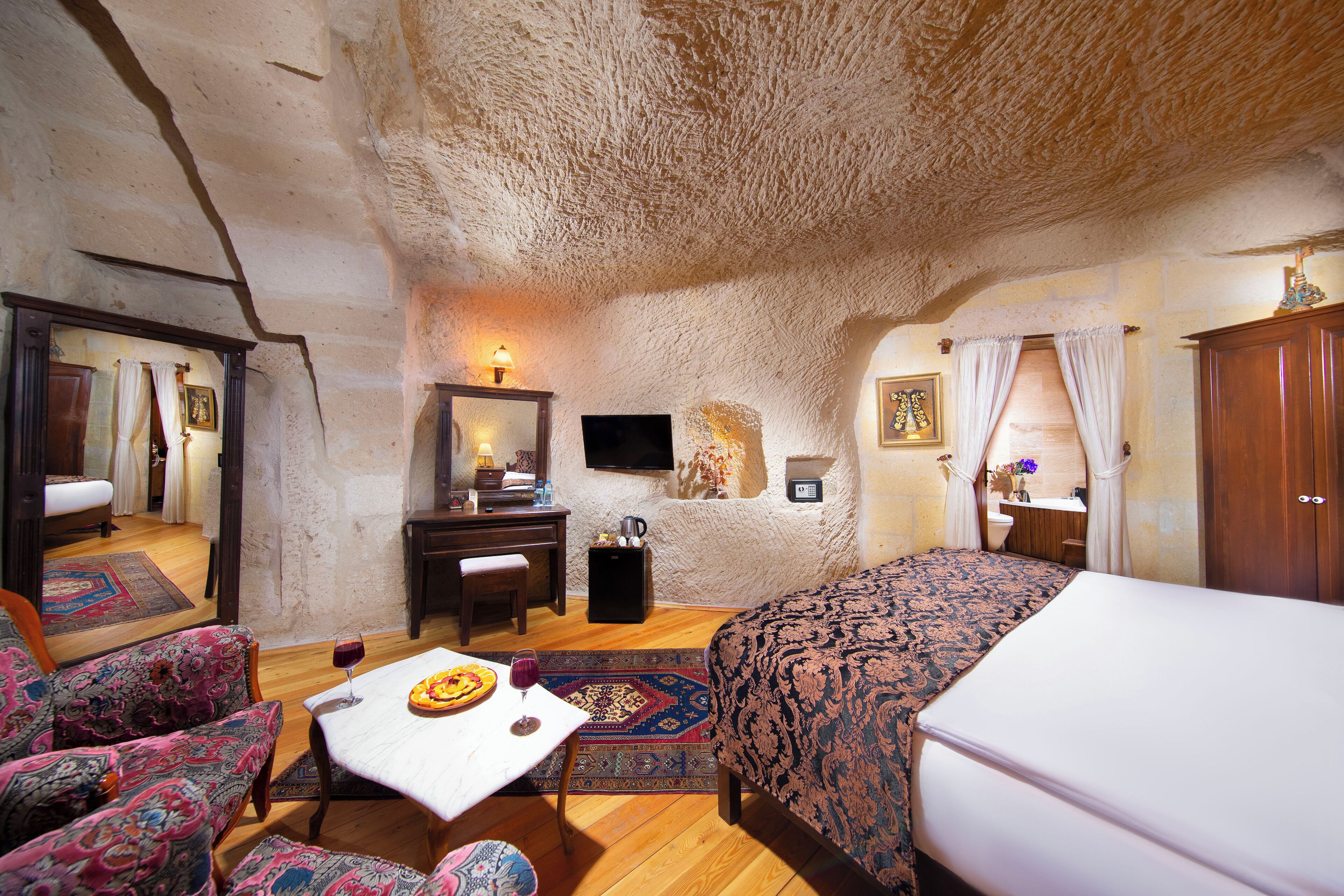 Une pièce confortable avec un lit, une table à manger avec une assiette et un verre, une chaise, une petite table avec une lampe et un miroir au mur.