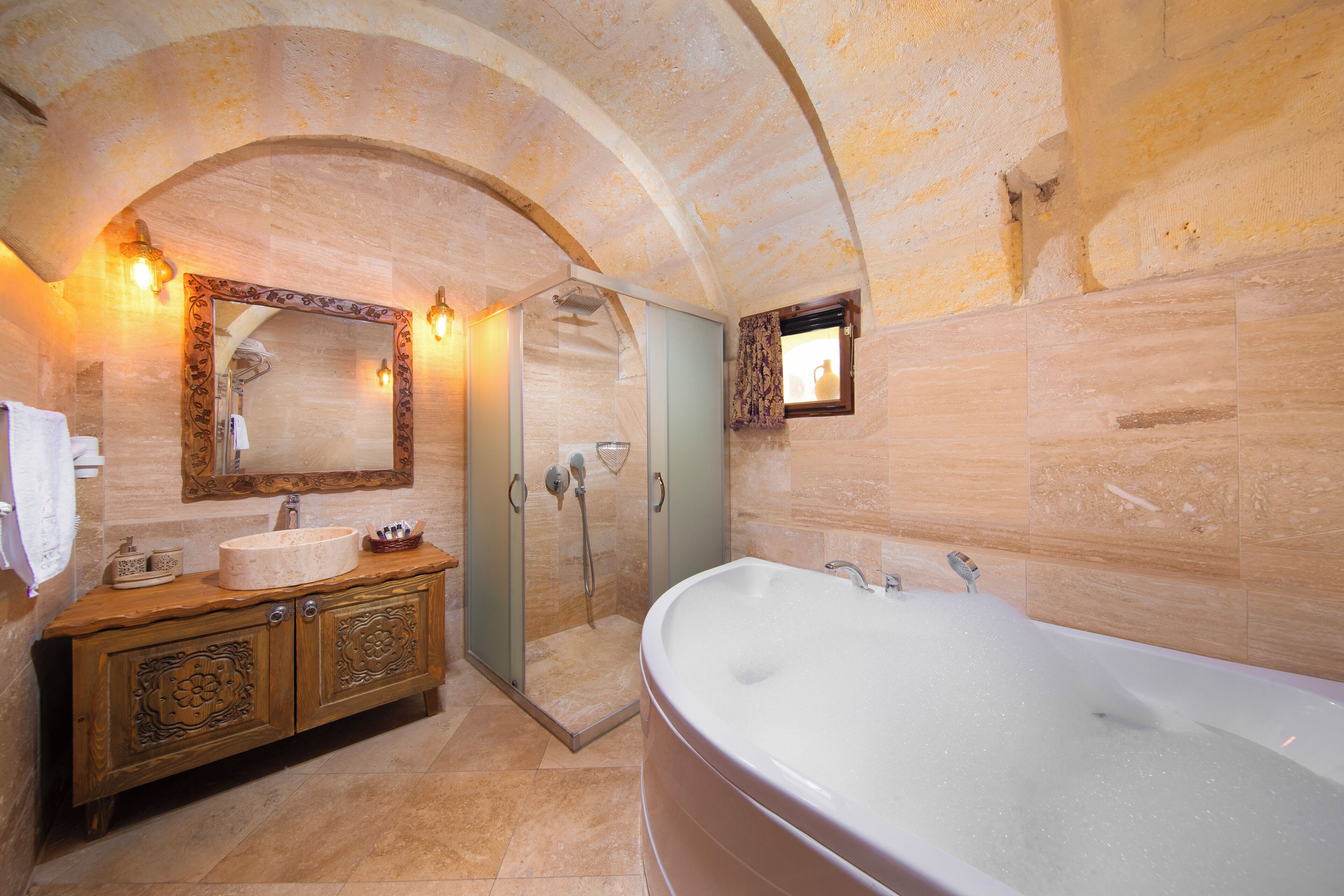 A bathroom with a large bathtub, a shower, and a vanity with a mirror and lights.