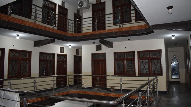 A multi-level interior with a central staircase, wooden doors, and a balcony. - Comfort Inn Hotel Peshawar (Mekhtar)
