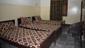 A room with two beds, a chair, a window with curtains, and a wall-mounted hook. - Comfort Inn Hotel Peshawar (Mekhtar)