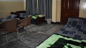 A room with two single beds, a chair, a small table, and a curtain. - Comfort Inn Hotel Peshawar (Mekhtar)