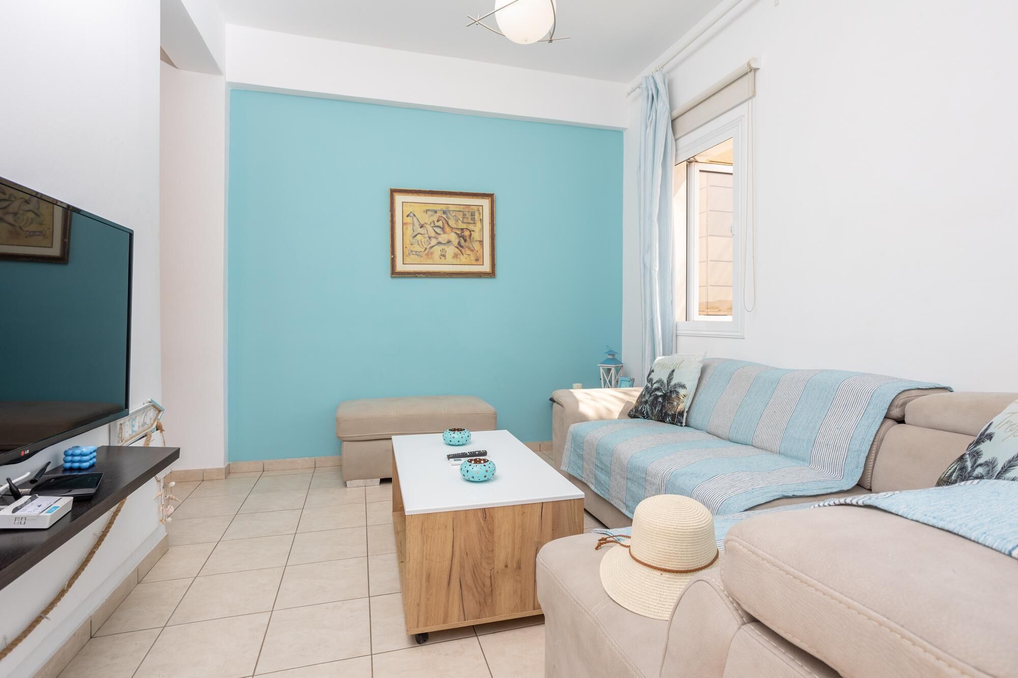 A living room with a blue wall, a sofa, a coffee table, a TV, and a framed picture.