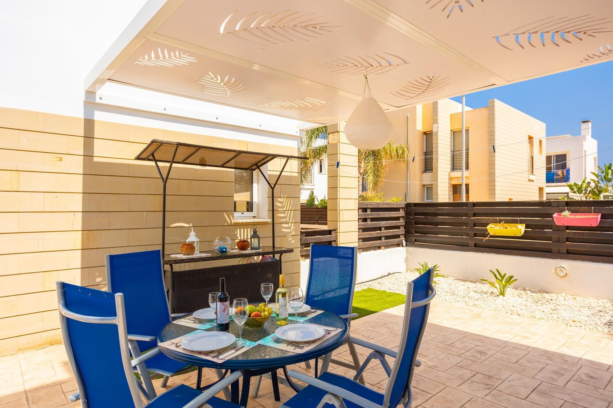 An outdoor dining area with a round table, blue chairs, and a grill.