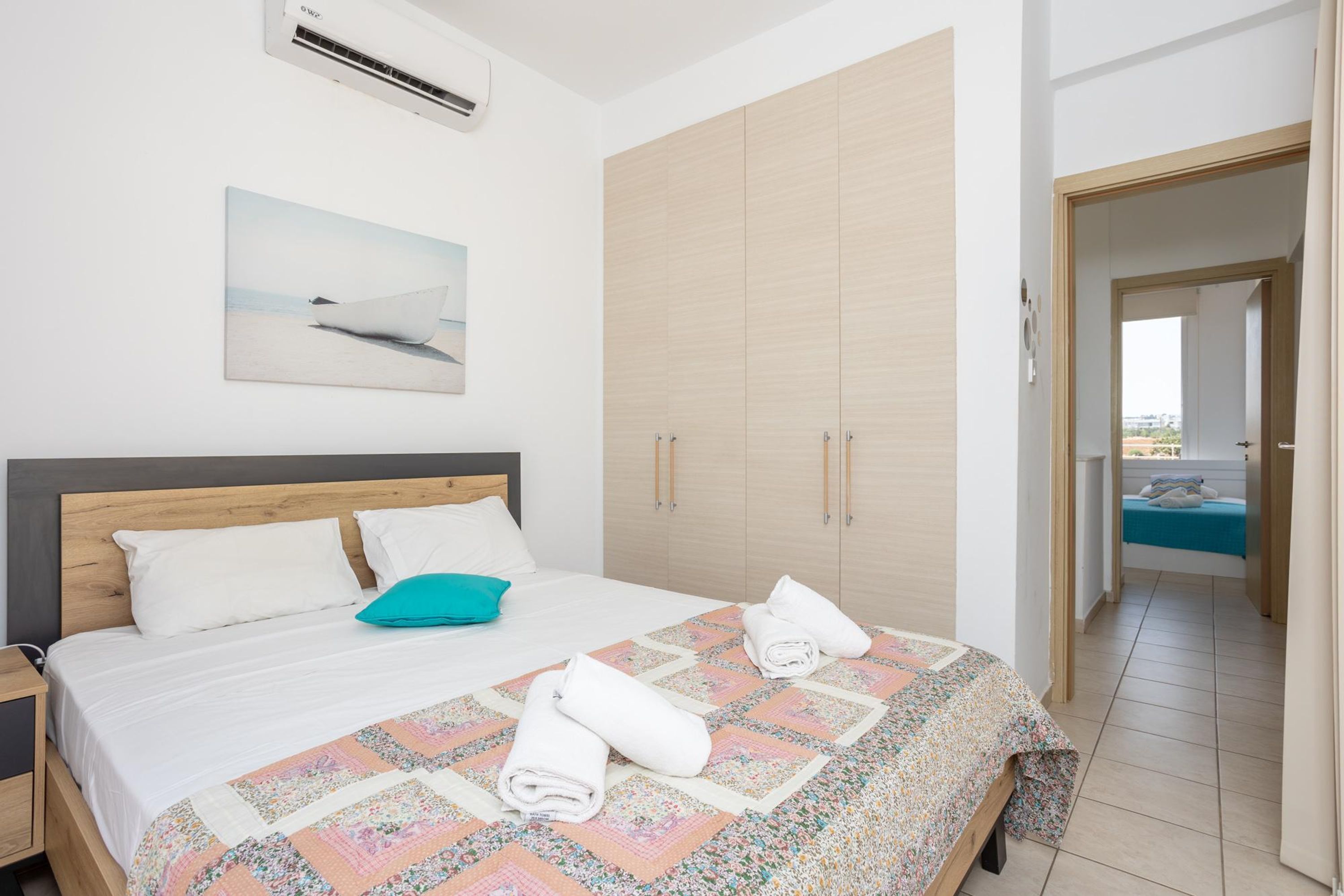 Un dormitorio con una cama grande, un armario de madera, un cuadro en la pared y vistas al balcón.