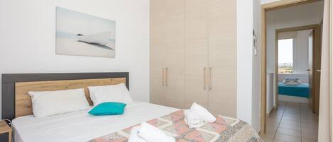 Un dormitorio con una cama grande, un armario de madera, un cuadro en la pared y vistas al balcón.