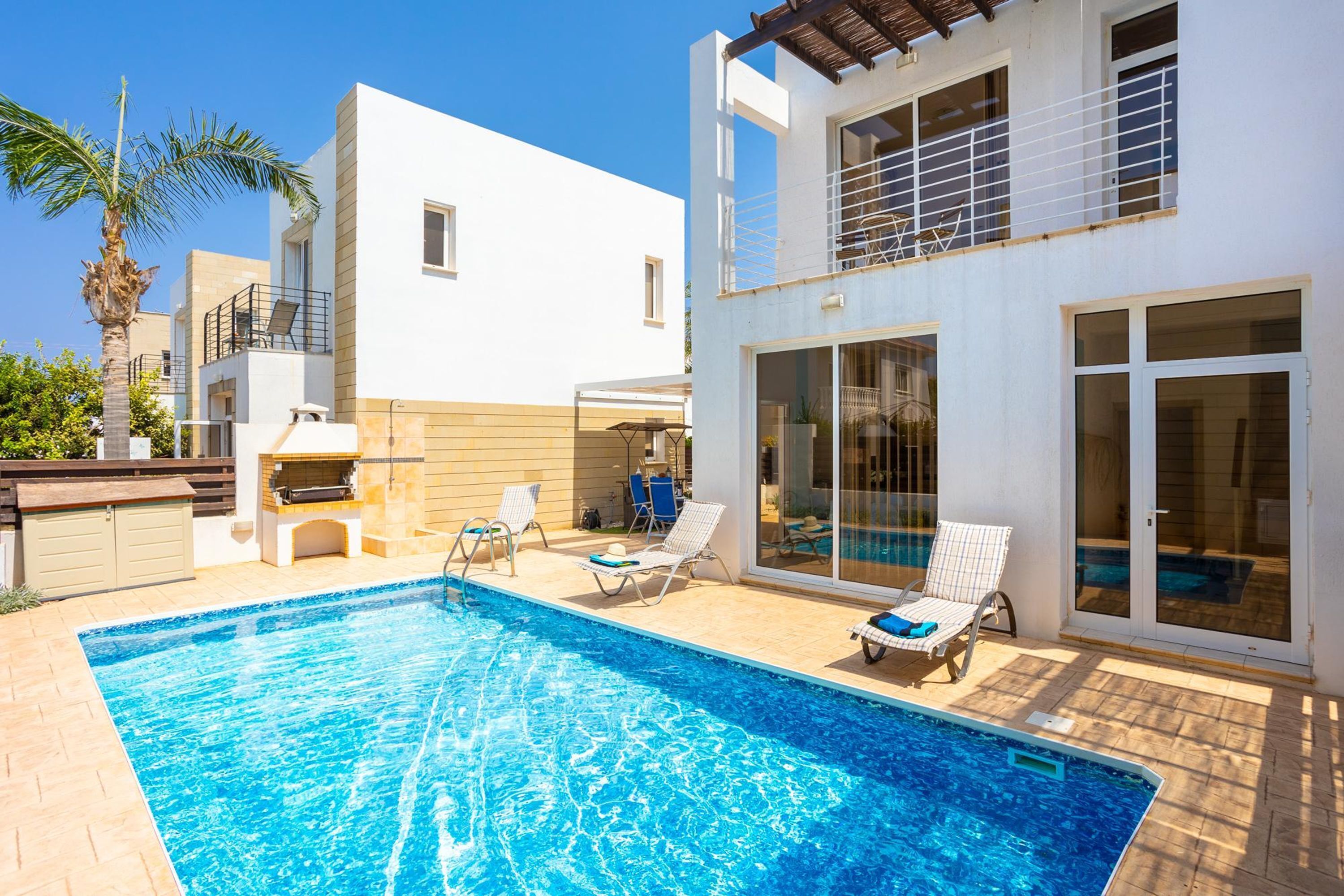 Een modern huis met een zwembad, buitenzitplaatsen en een terras.