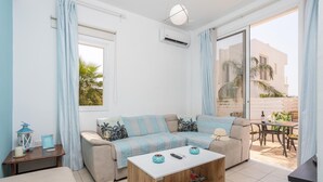 A modern living room with a sofa, coffee table, and a view of the outdoor patio. - Villa Vitamin Blue in Pernera (Paralimni)