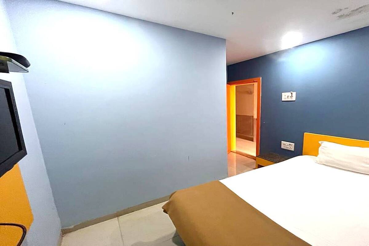 A hotel room with a bed, a television, and a door leading to another room.
