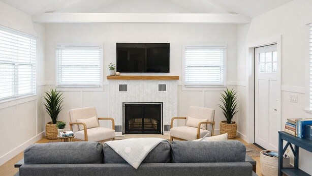 A spacious living room with a fireplace, two armchairs, a sofa, and a TV mounted above the fireplace. - Book & Stay Today + King Bed + Beach Chairs (Indian Rocks Beach)