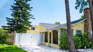 A residential property with a covered patio, a stone chimney, and a gated driveway. - Book & Stay Today + King Bed + Beach Chairs (Indian Rocks Beach)