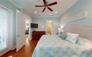 Relax in this inviting bedroom with a large bed, ceiling fan, flat-screen TV, and dresser.