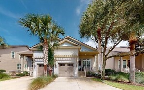 Stunning two-story home with a central entrance, covered porch, and garage door, set amidst beautifully maintained gardens.