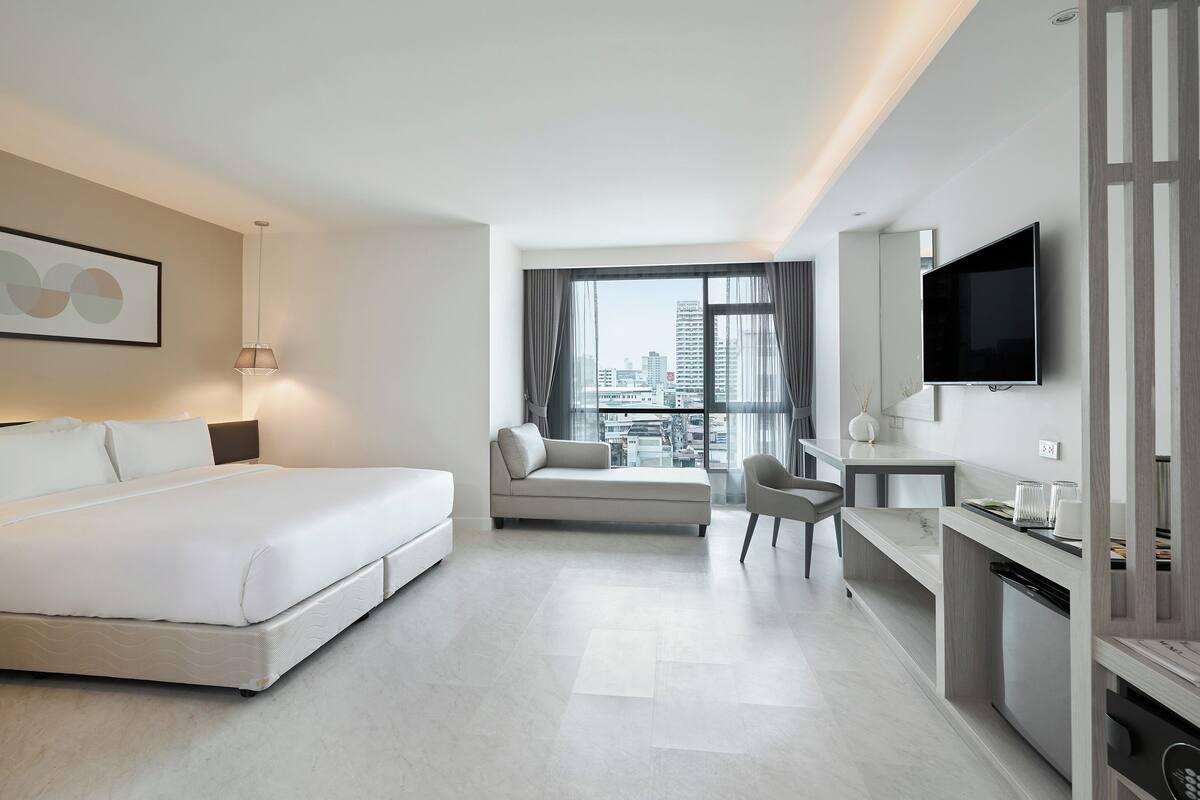 Una habitación de hotel moderna con cama, sofá, escritorio y televisor.