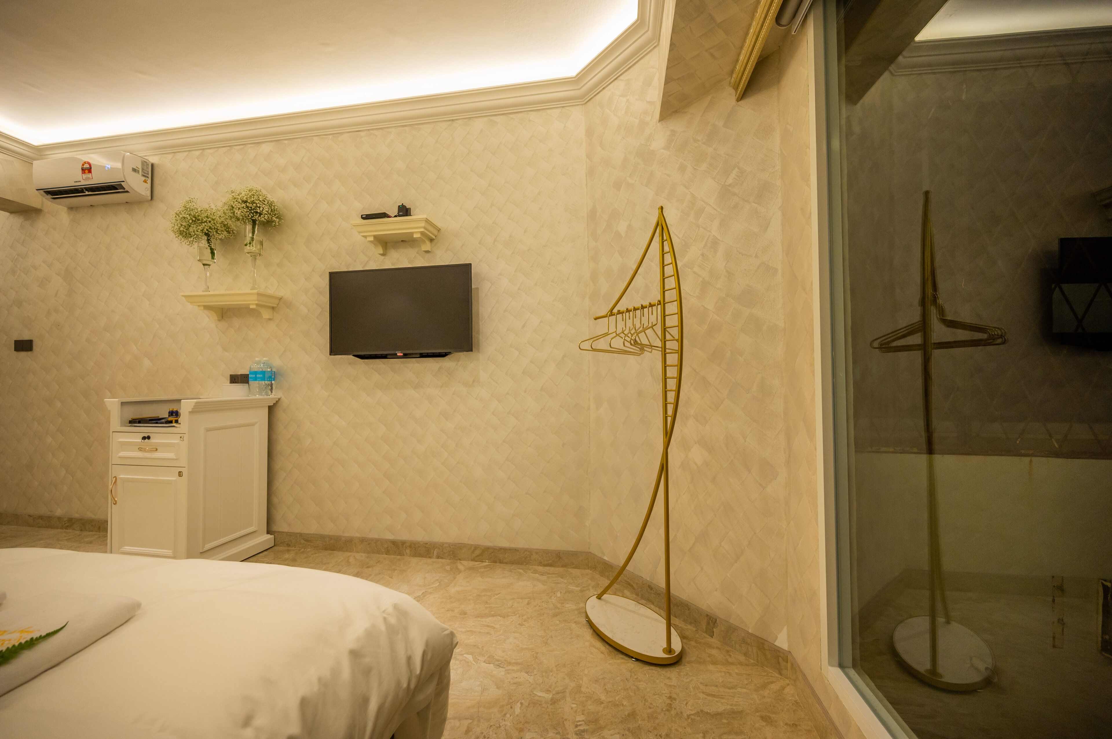 Une chambre d’hôtel comprenant un lit, un téléviseur fixé au mur, un petit meuble et une structure décorative en forme d’échelle.