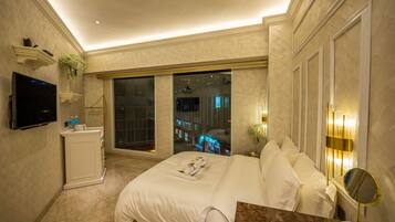 A hotel room with a bed, a TV, a desk, and a window with a city view.