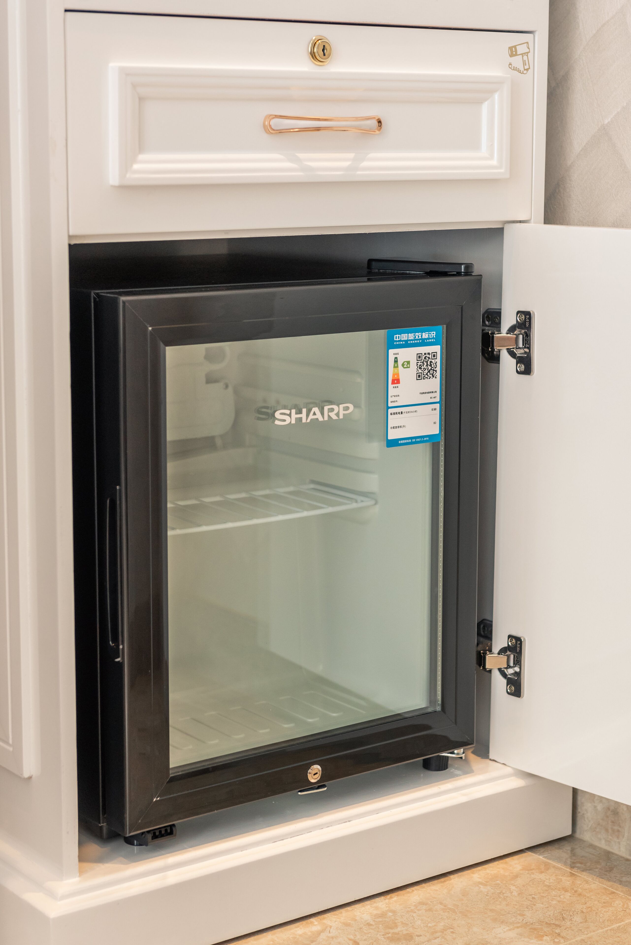 A kitchen with a built-in microwave oven, a white cabinet above it, and a door with a QR code sticker.