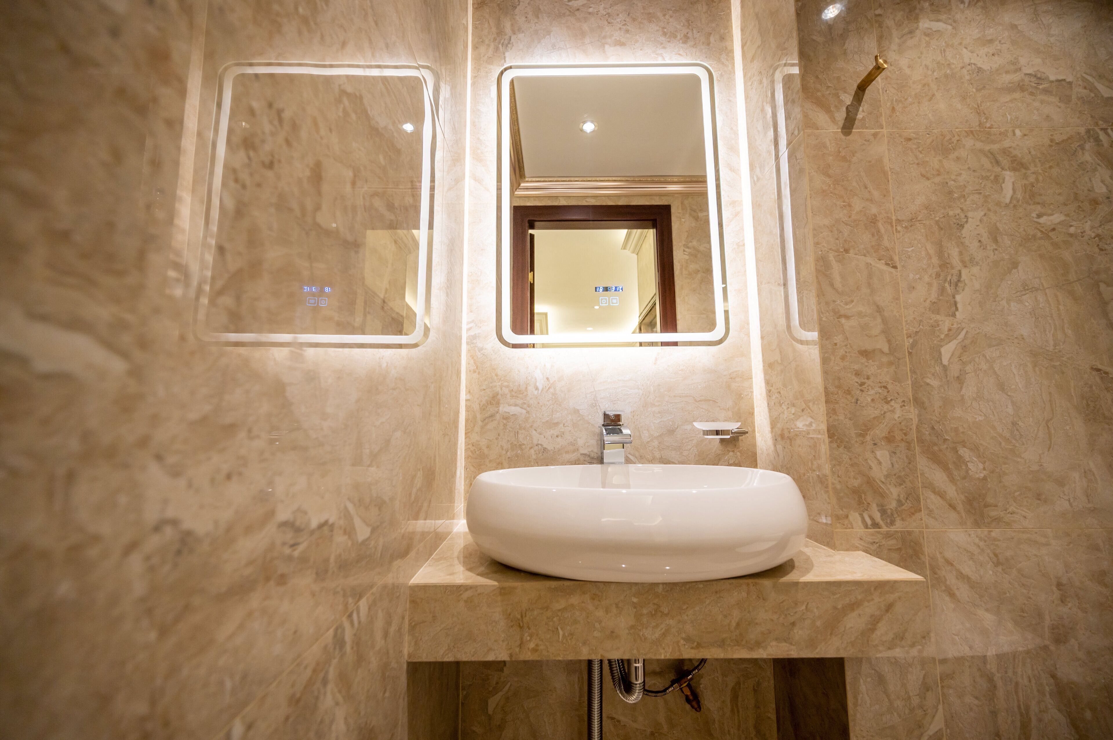 A bathroom with a large oval sink, a mirror, and a showerhead.